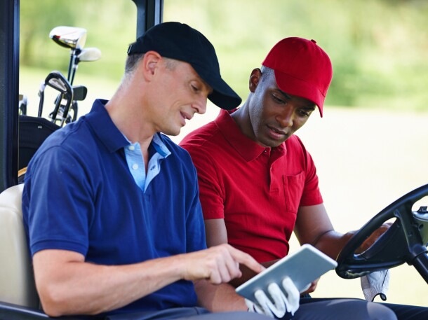 Shot of two men in a golf cart looking at a digital tablet